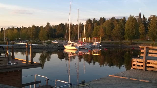 Nurmeksen keskustan matkustajasatamassa purjeveneitä ilta-auringossa. Taustalla näkyy Nurmeksen kirkon torni