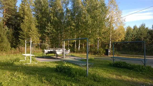 Betonilaatan päällä matonpesualtaita kuivaustelineineen koivikon reunassa aurinkoisena päivänä