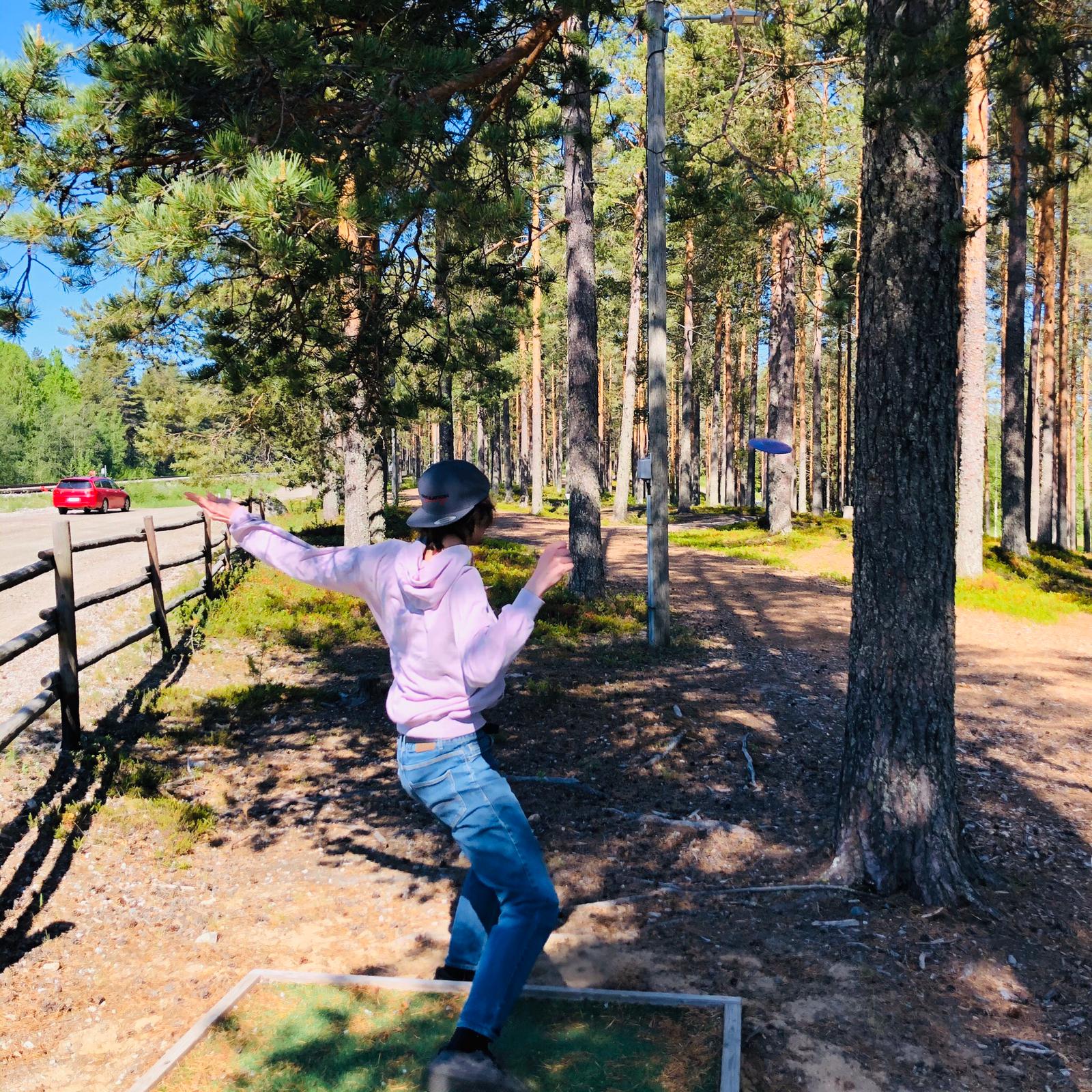 Poika heittää frisbeegolfia