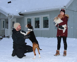 Mies ja nainen talon edessä silittelemässä koiria.